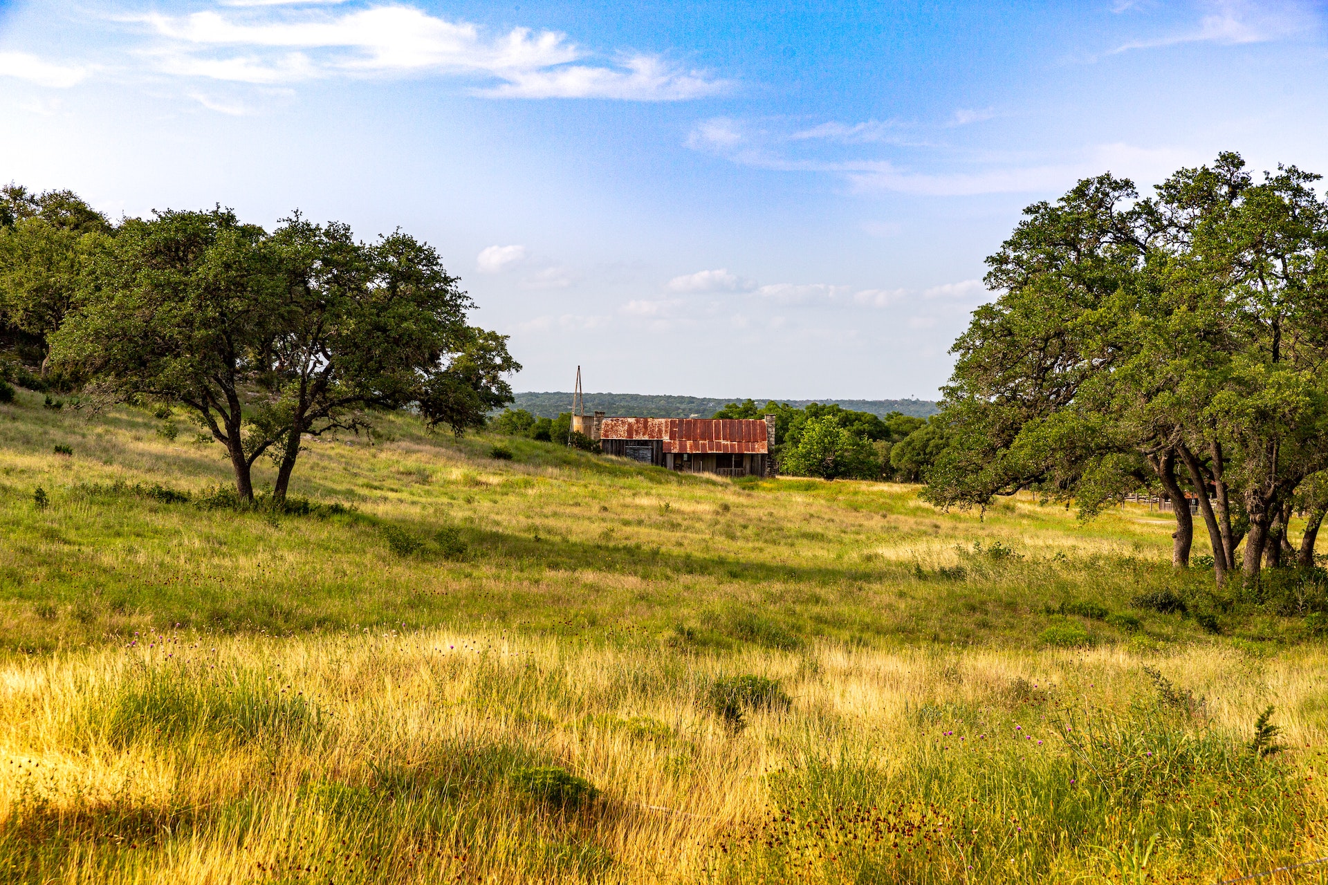 Rolling fields and a barn beneath blue skies in Texas Hill Country