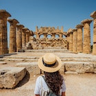 Rear view of a woman with a hat while she's admiring an ancient temple in Sicily. Sunny day. Cool straw hat.
1364745633