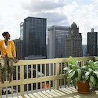 Chicago, Illinois, USA.
200443137-003
A young woman sitting on a rooftop railing with the Chicago skyline in the background