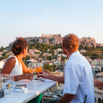 Couple drinking and enjoying the view of the Acropolis at sunset. Athens, Greece