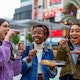 Group of Friends Eating Take Away Food on the Street in Tokyo.