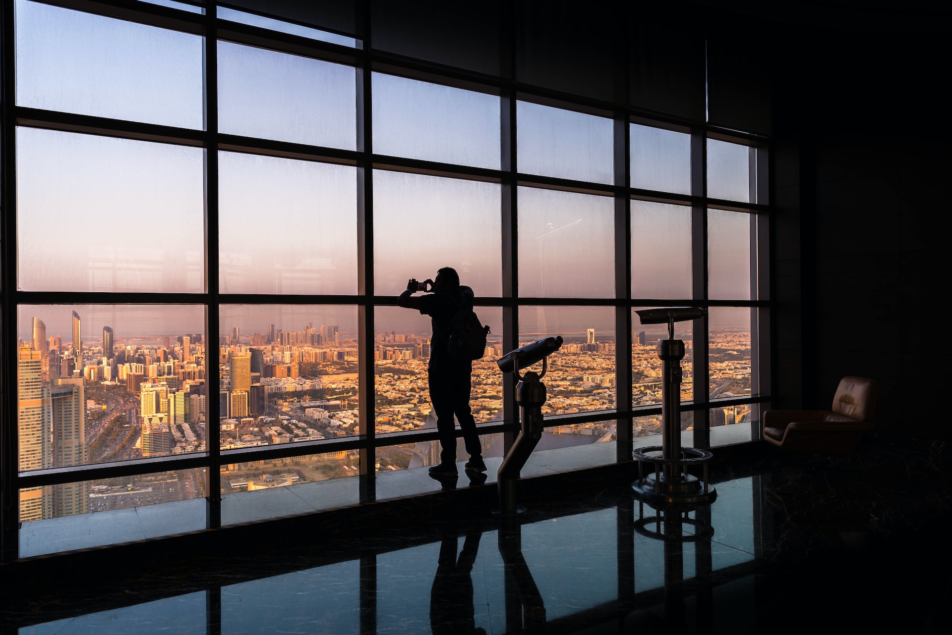Silhouette of tourist taking picture with smartphone from Observation Deck at 300, Etihad towers